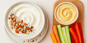 Bol de skyr avec amandes et graines de chia, crudités colorées et houmous, texte « 2 collations saines qui coupent la faim ».